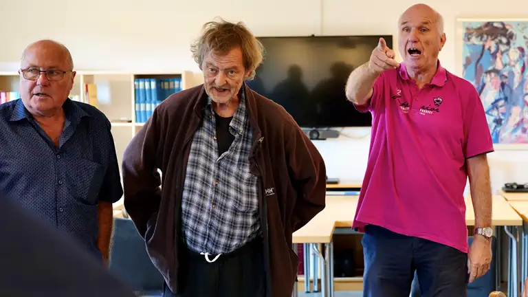 Tre deltagere fra demenskoret står og synger